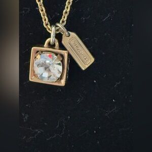 Coach gold tone necklace. Dangly gem with gold around with coach tag.
